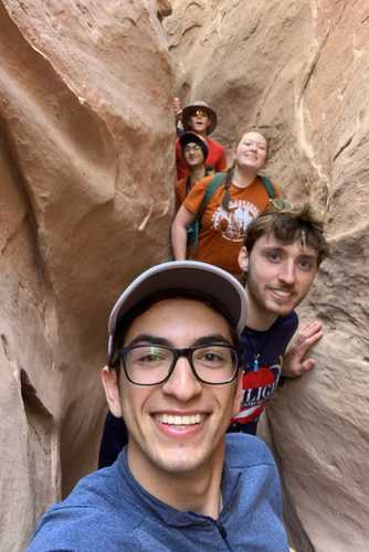 A line of undergrad students taking a selfie within a narrow rock crevasse. 