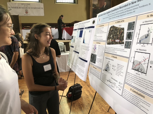 Maria discusses her research poster with a fellow student. 