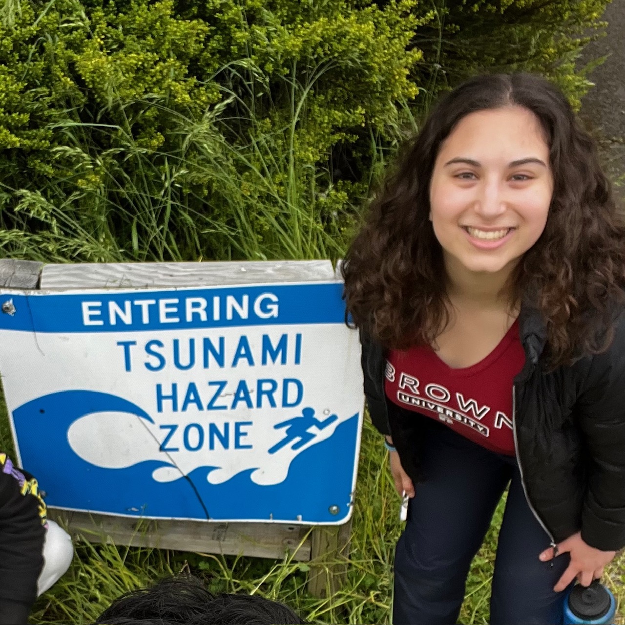 Allison Cavallo beside a tsunami hazard zone sign