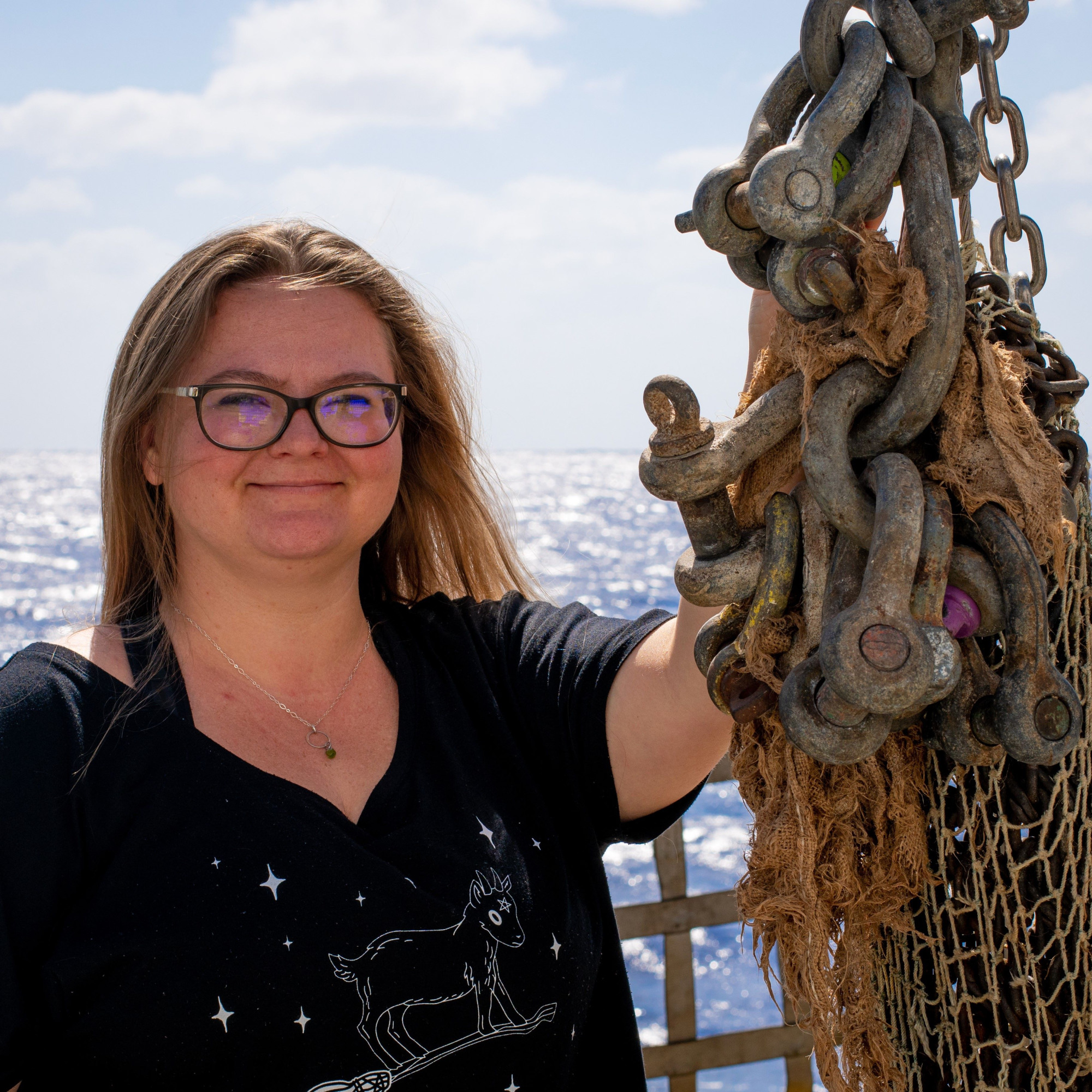 Olivia posing beside a dredge basket on the R/V Kilo Moana in the Western Pasific ocean.