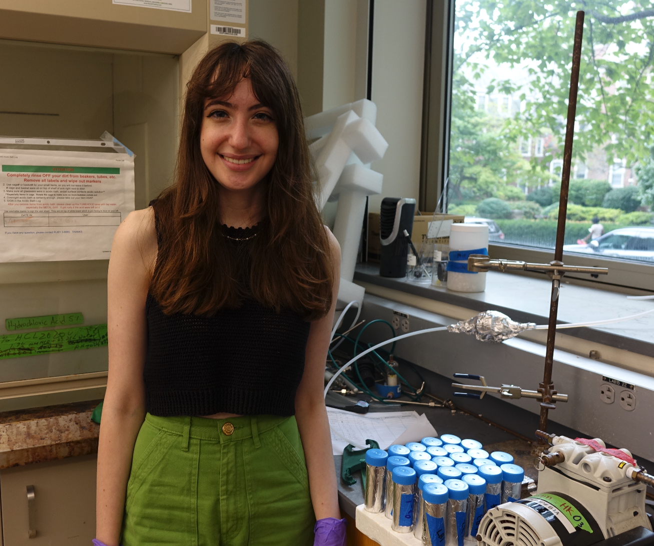 Emma in the lab smiling beside samples