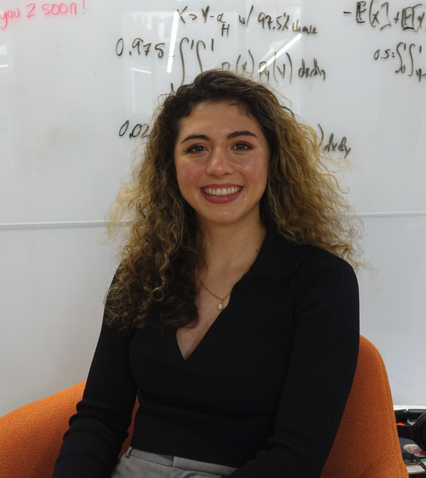 Abrielle smiling in front of a whiteboard with equations 