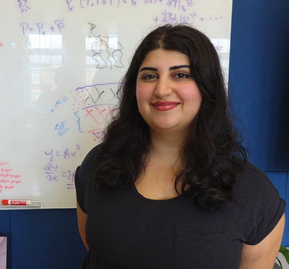 Ariyana smiling in front of a whiteboard with equations. 