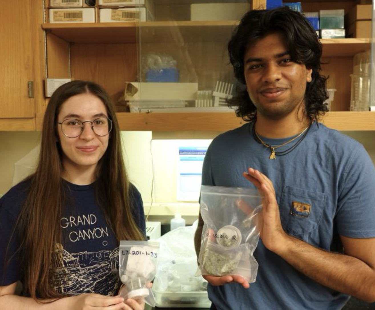 Shannon and Dev pose holding bags of rock samples