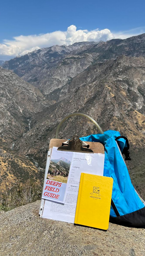 The Field Guide brochure on a clipboard with the Alaskan mountains behind