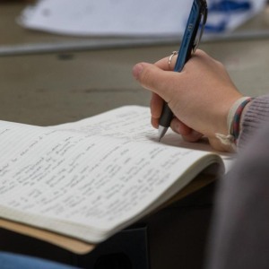 A closeup photo of someone writing notes in a notebook. 