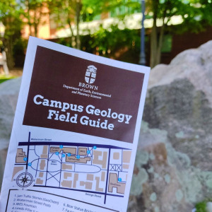 A copy of the Campus Geology Field Guide in front of the Jan Tullis Memorial Stones outside GeoChem.