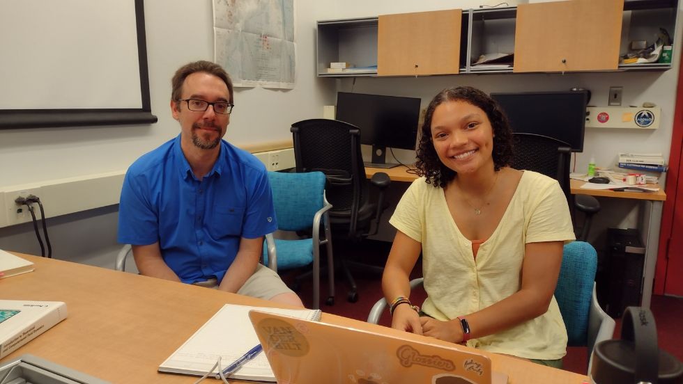 Student and professor sitting at a laptop smiling for the photo. 