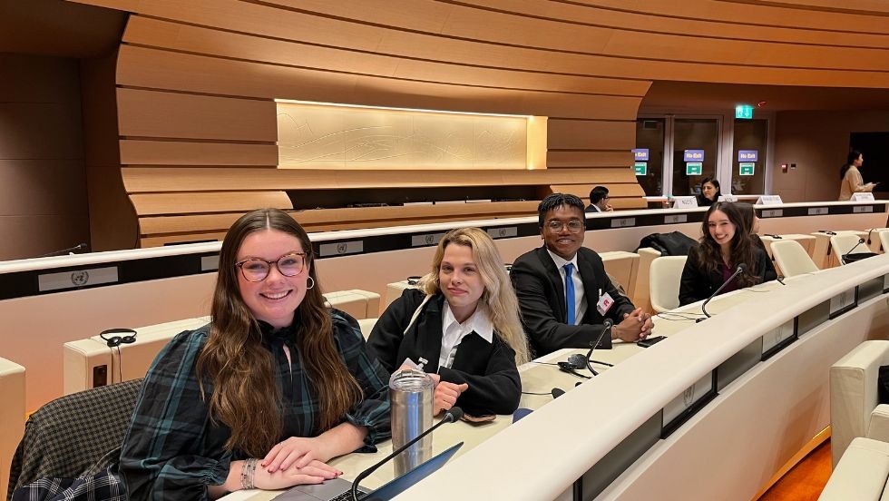 Four students posing for a photo seated in the United Nations conference. 