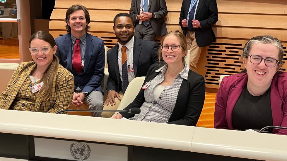 Five students posing for a photo seated in the United Nations conference. 