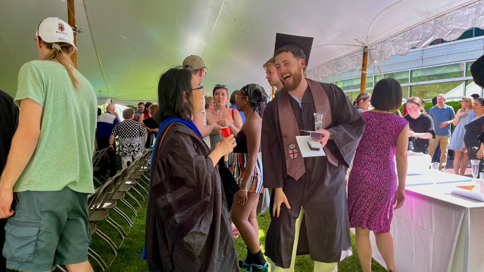 A graduate and faculty laugh at the commencement reception. 