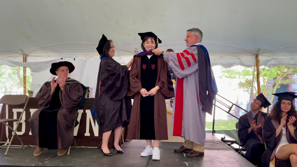 Fox-Kemper and Lee bestowing Rosa Xu her hood and diploma. 