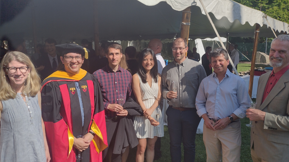 Seven faculty members smile for a photo at the commencement reception. 