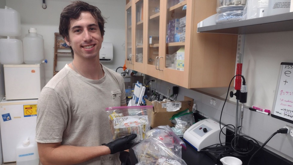 Jonah holding a bag of samples in the lab. 