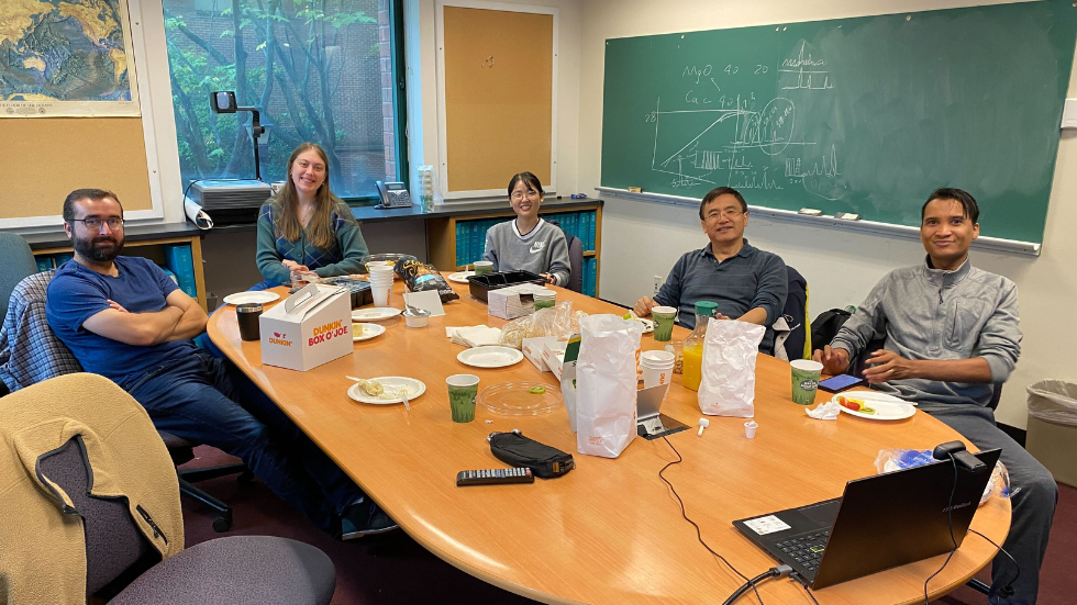 Five DEEPS researchers around a conference table smiling. 