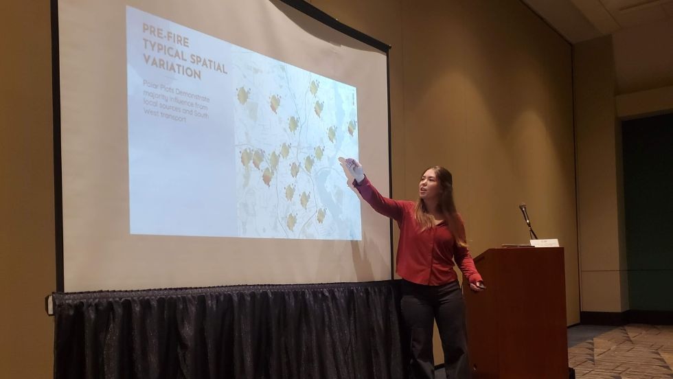 Kathryn Farber pointing at a Powerpoint presentation in a conference room. 