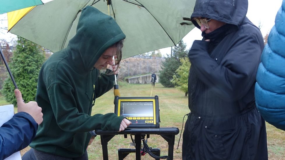 Hannah and Annalisa review data on the GPR screen under umbrellas. 