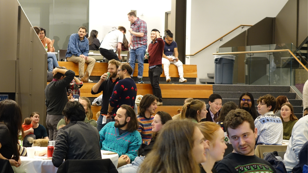 A crowded room of DEEPS students, faculty, staff, and friends mingling at the holiday party.