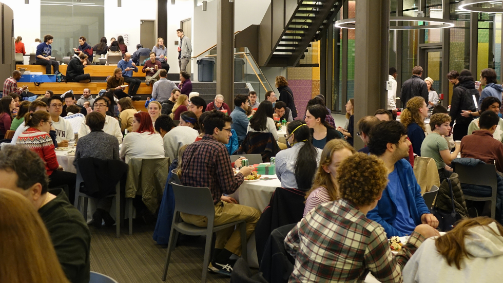 A crowded room of people mingling at the holiday party. 