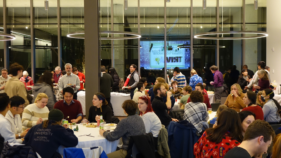 A crowded room of DEEPS students, faculty, staff, and friends mingling at the holiday party.