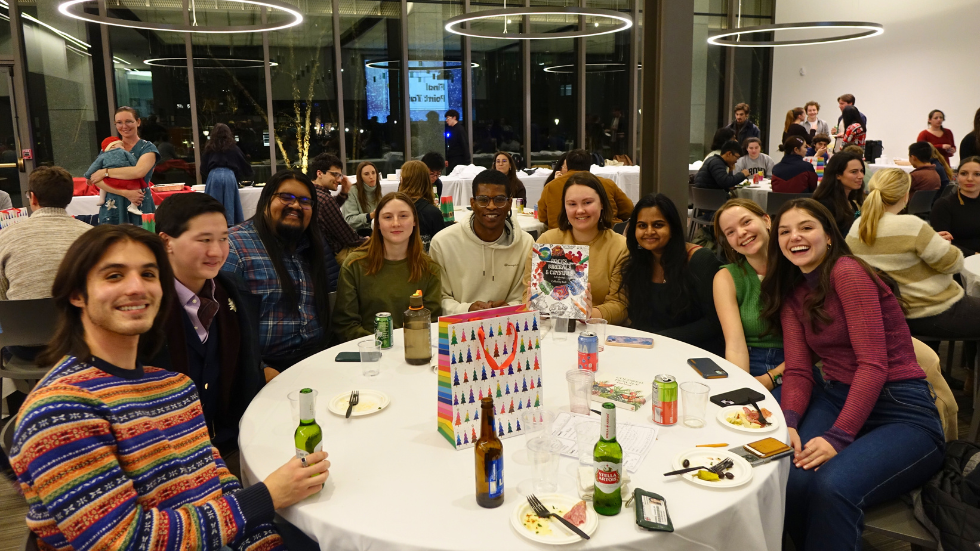 A table of grad students smile for a photo together.