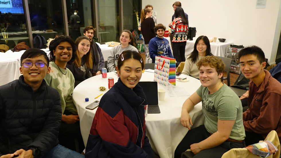 A table of undergrad students smile for a photo together.