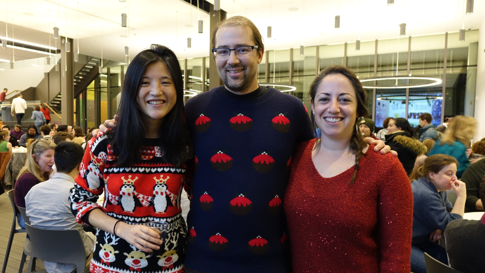 Three new faculty in holiday sweaters pose for a photo together. 