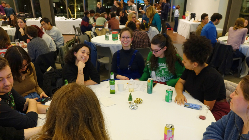 A table of grad students playing the trivia game and smiling for the photo. 