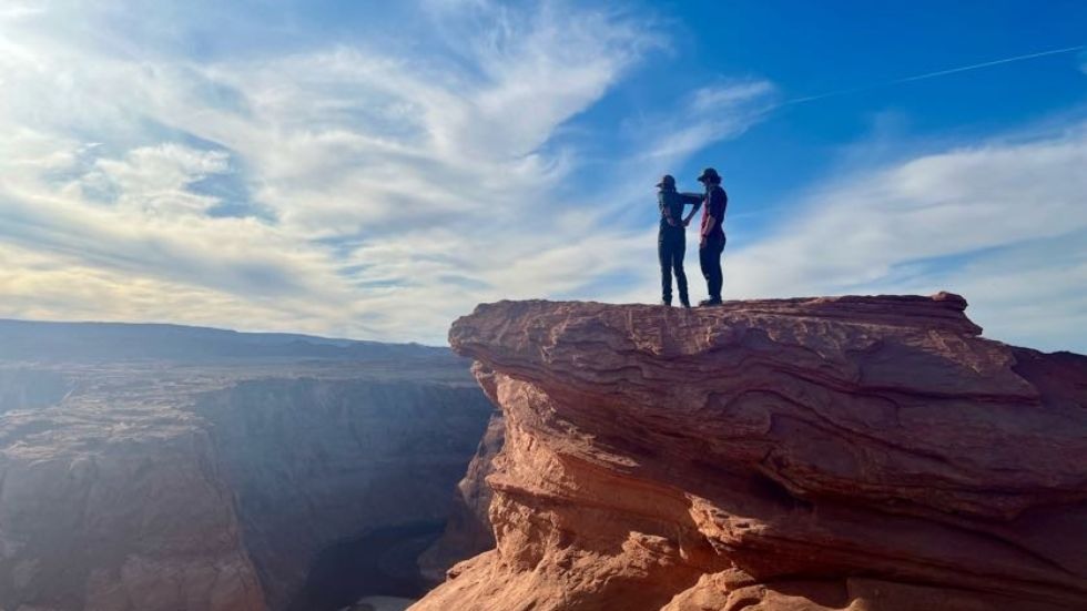 Two students standing on a high ledge above the canyon