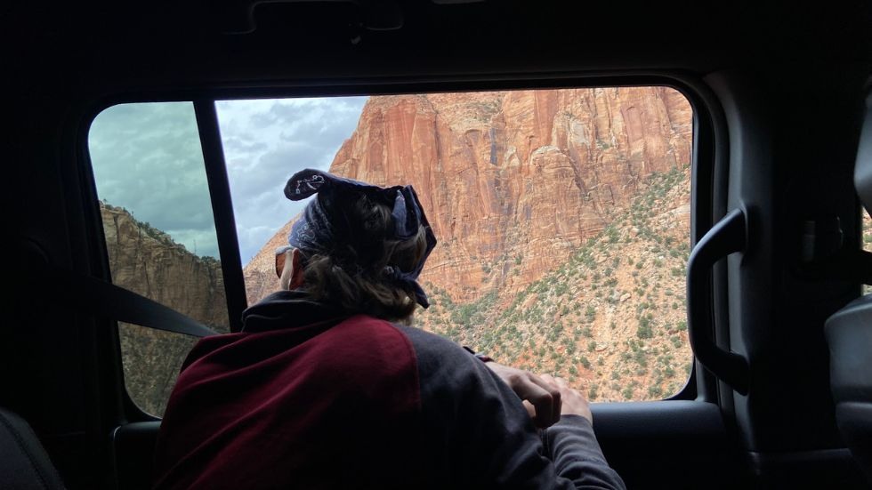a student looking out a car window to watch the view of the canyon go by 