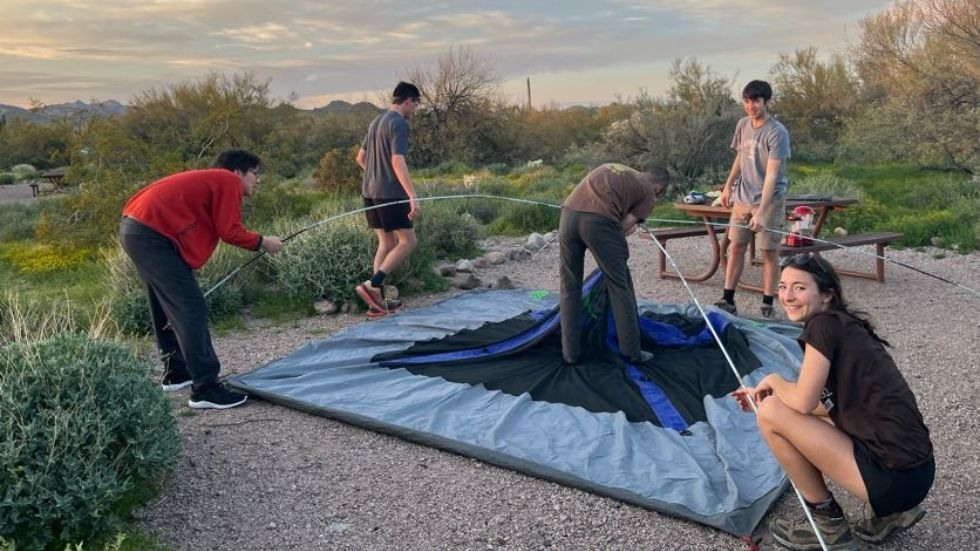 students work together setting up a tent