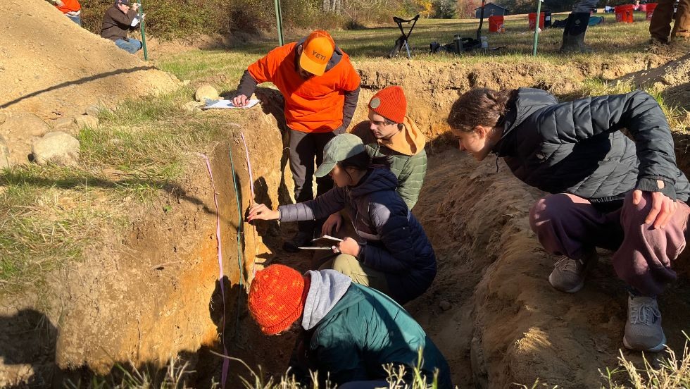 students working in a hole taking measurements of the soil. 