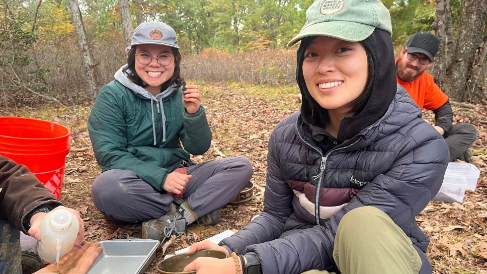 two students smile holding soil samples