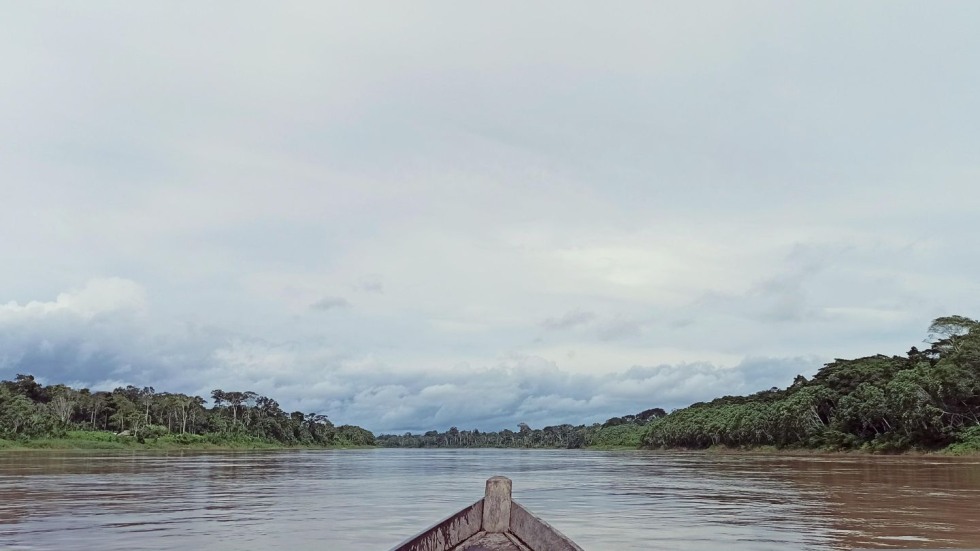 Photo of the Amazon river from within a boat, with clouds over the horizon. 