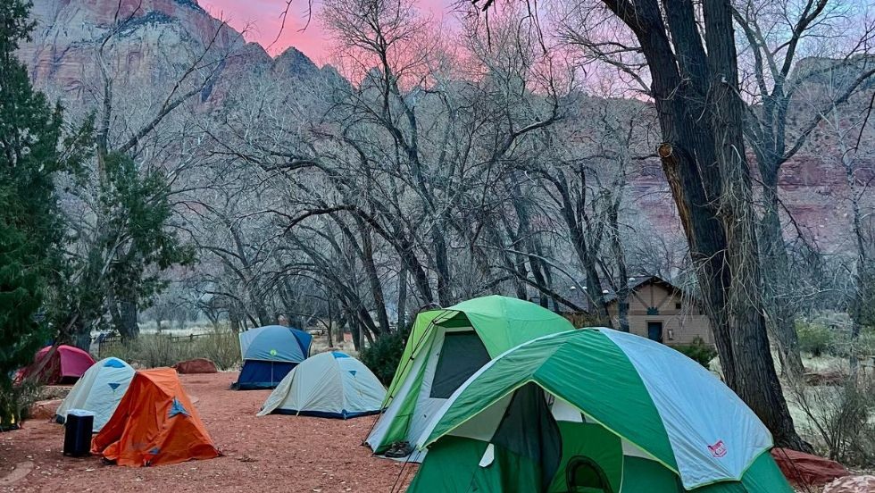 a collection of tents under a pink sunrise and mountains