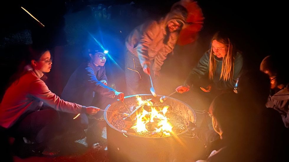 students roasting marshmallows over a campfire