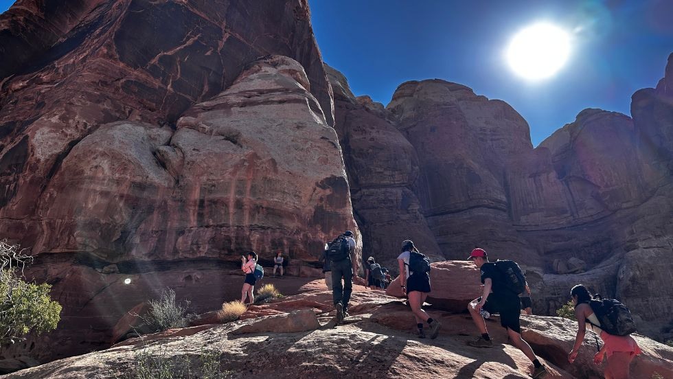 student hiking up a rocky trail