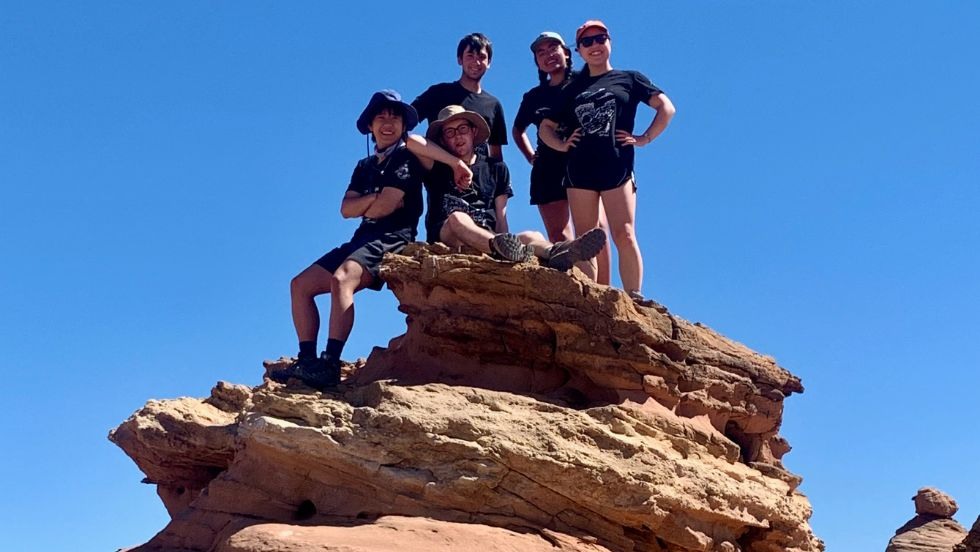 students posing on top of a tall rocky outcropping