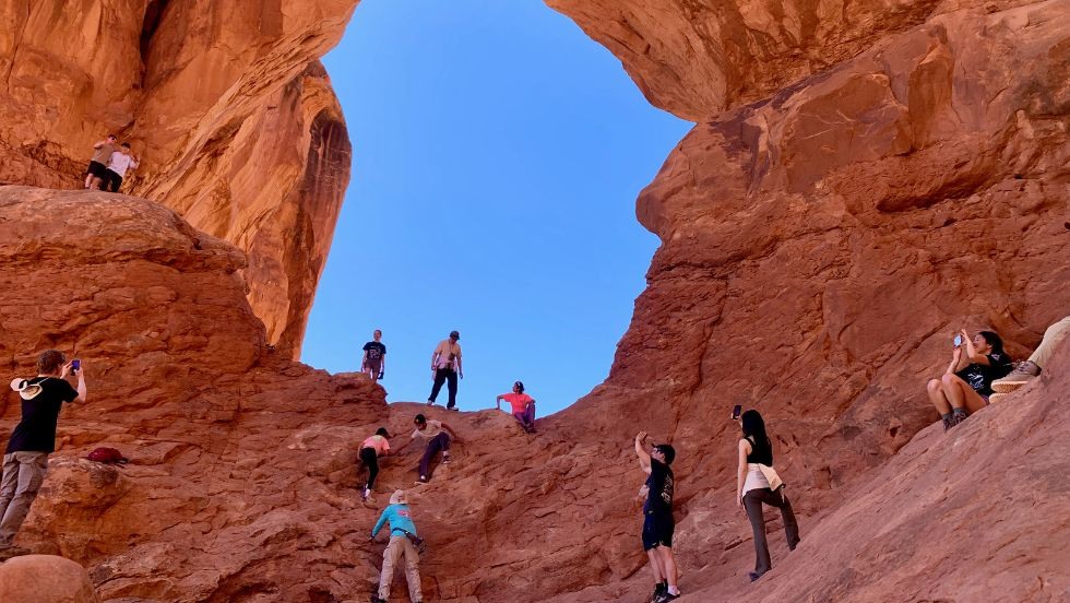 students hiking up a unique rock arch