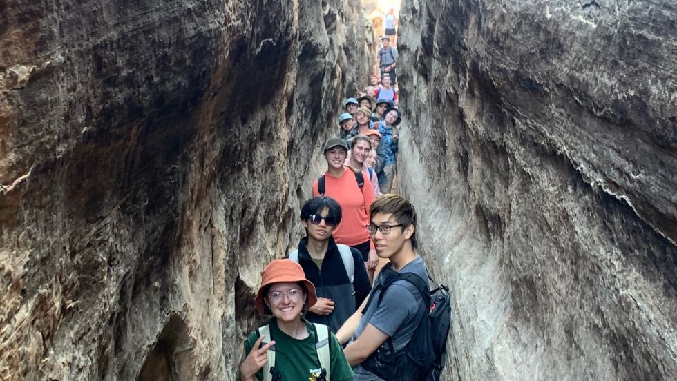 students taking a selfie within a narrow rock crevasse