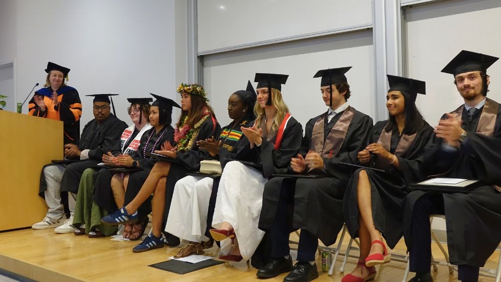 students on stage applaud all graduates and award winners