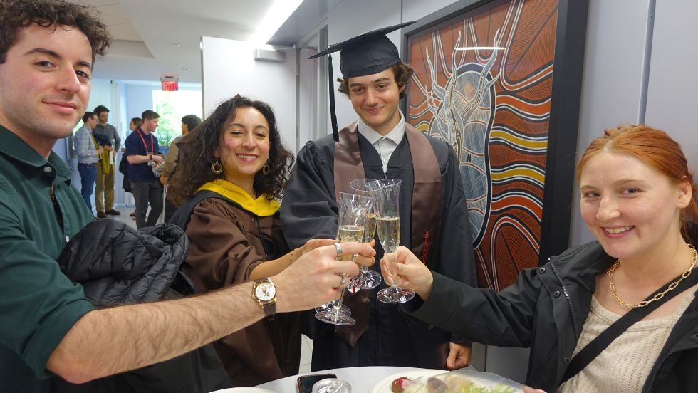 two graduates and two guests toast after the ceremony