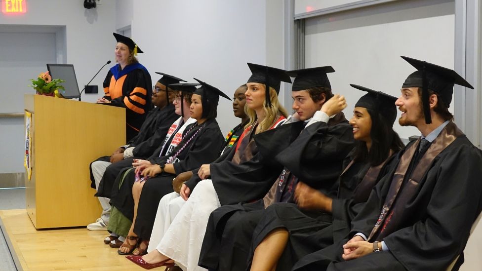 graduating undergrads seated together on stage as Chair Hastings begins