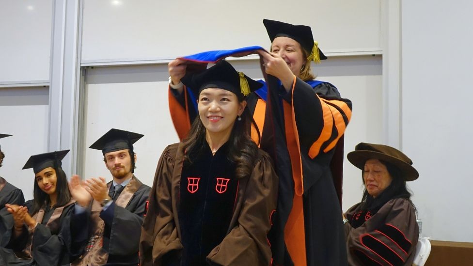 Chair Hastings bestowing graduate hood on Heejeong Kim