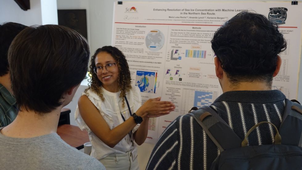 a graduate student discusses her research poster with peers 