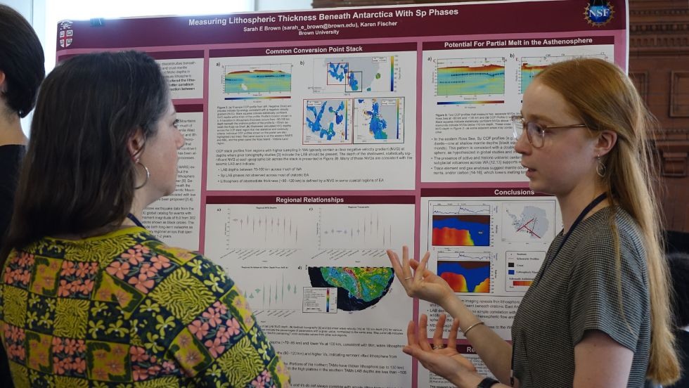 a graduate student discusses her poster with a faculty member 