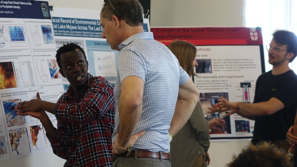 a graduate student discusses his research poster with a faculty member 