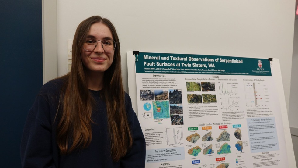 an undergrad posing beside her poster 
