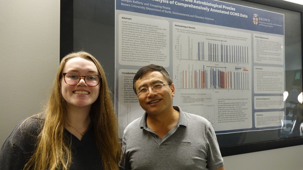 a student and her advisor pose in front of her poster 