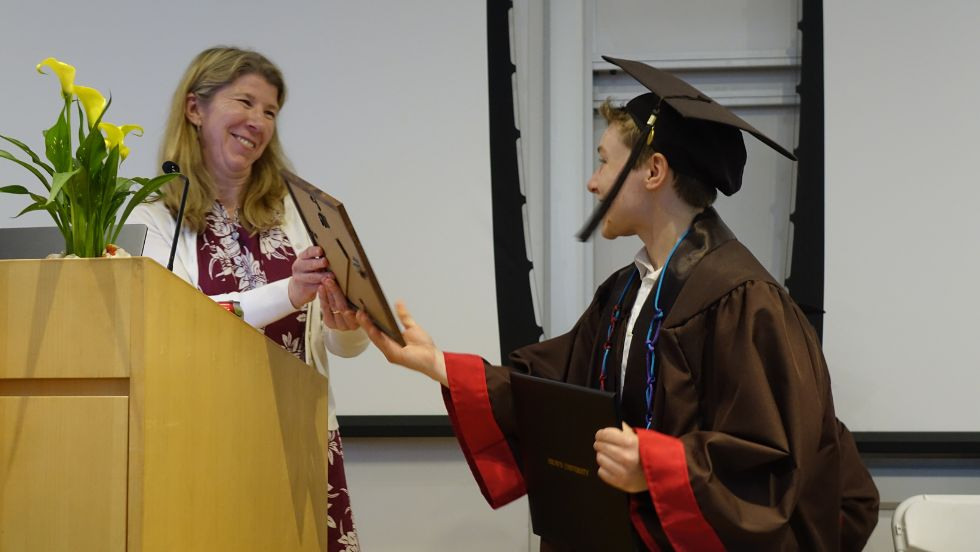 an undergrad and professor smile while bestowing their award 